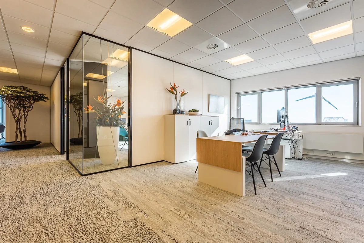 Modern en licht kantoorinterieur in Rivium Quadrant met glazen vergaderruimte, bureau en grote raampartijen.